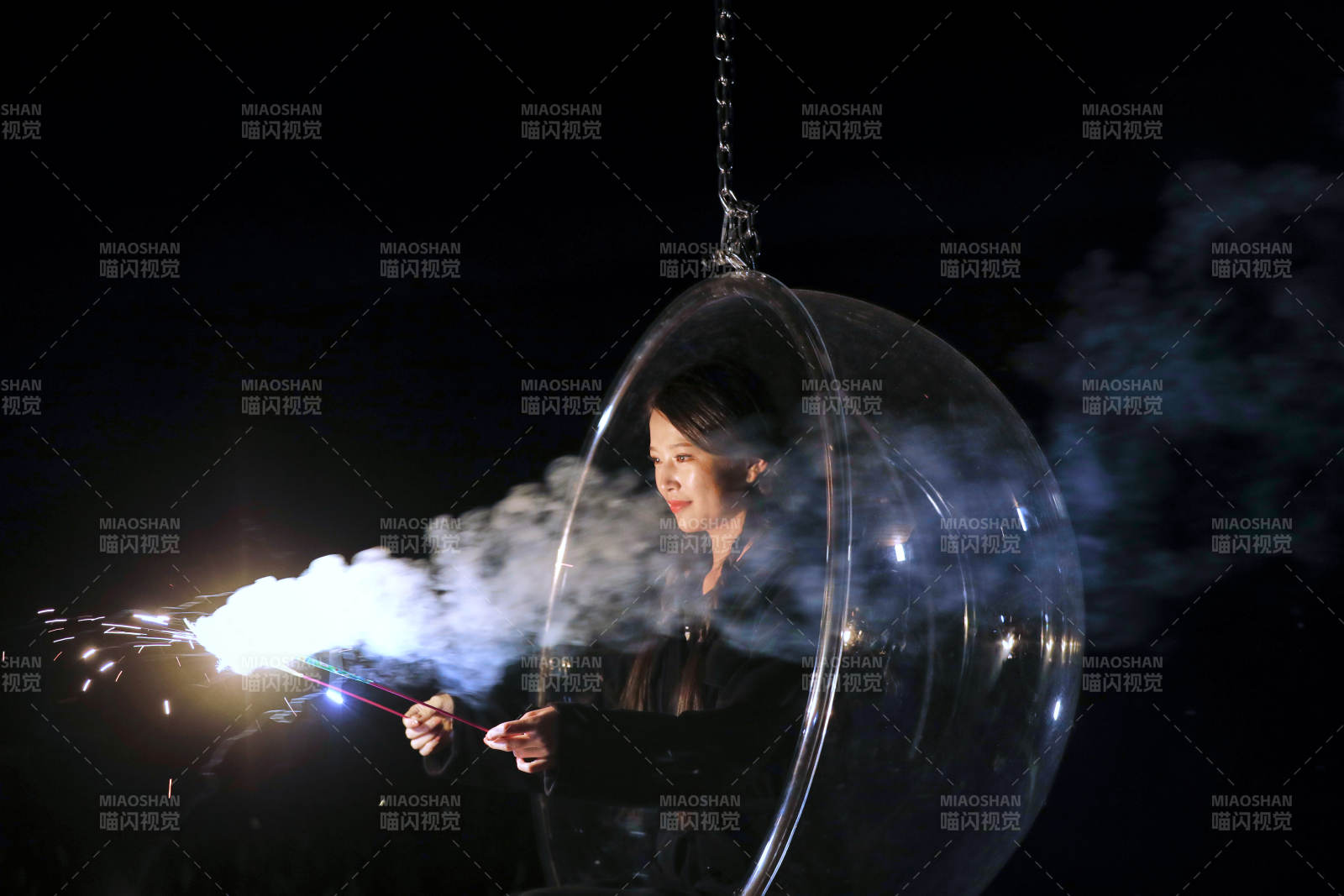 夜晚坐在透明秋千上燃放仙女棒的可爱少女