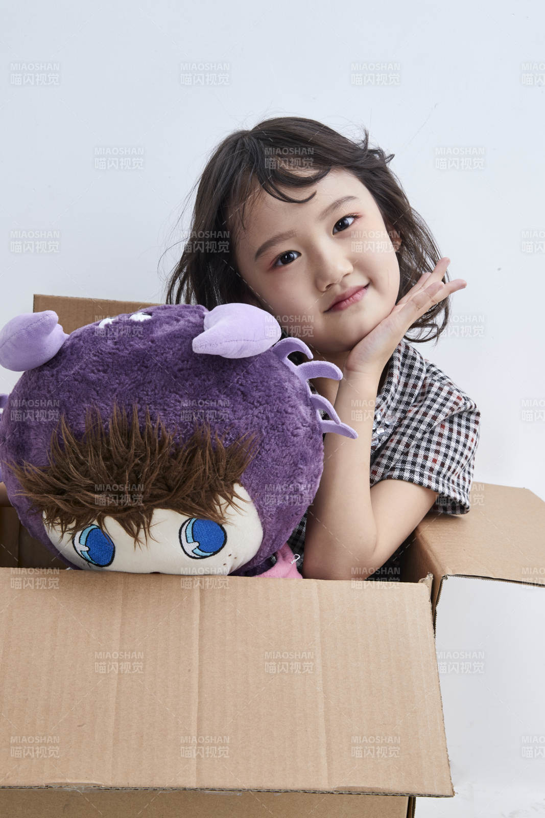 黑色背景里坐在凳子上抱着娃娃玩耍的可爱亚洲小女孩儿童