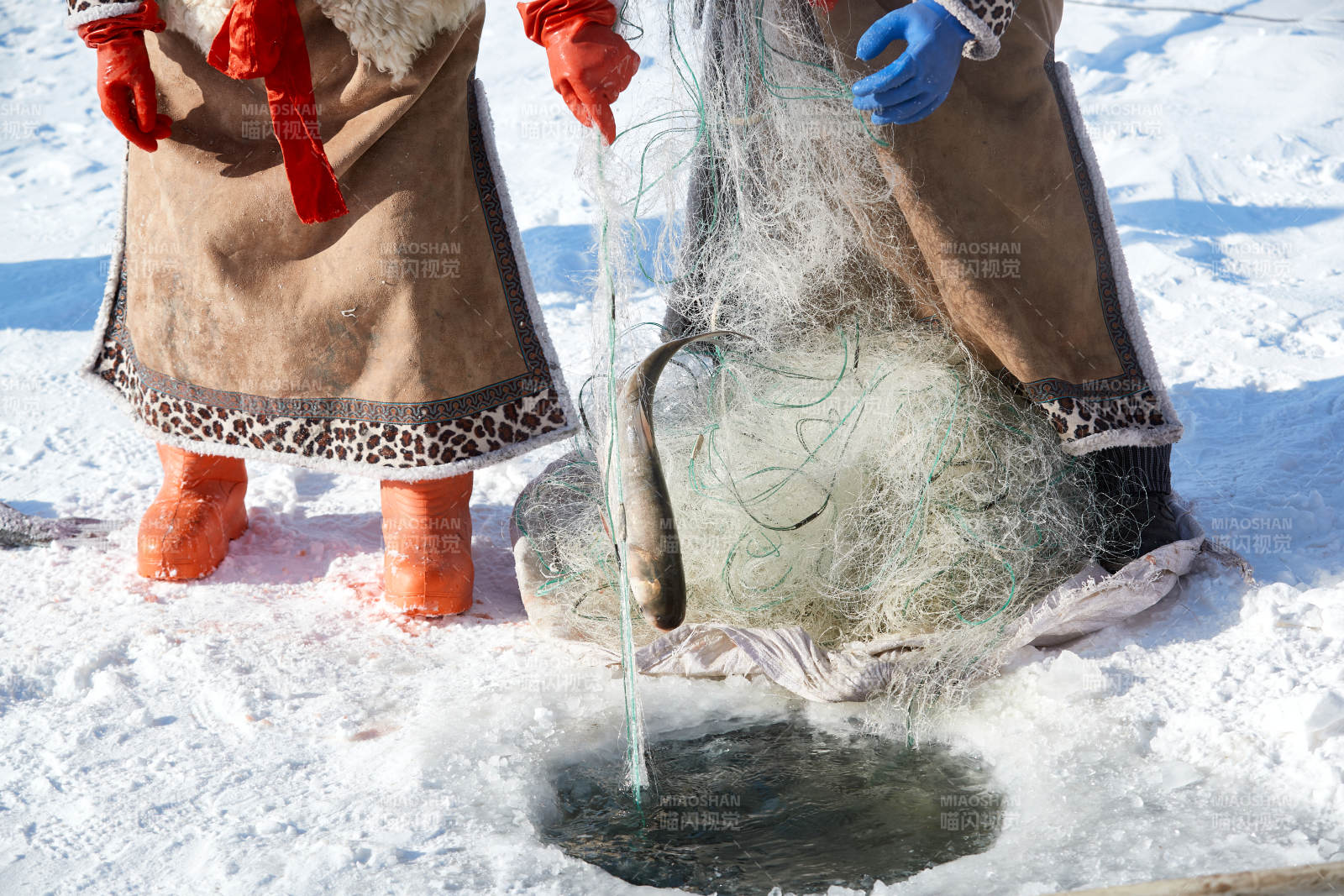 寒冷的冬季在冰凍的湖面上鑿冰捕魚