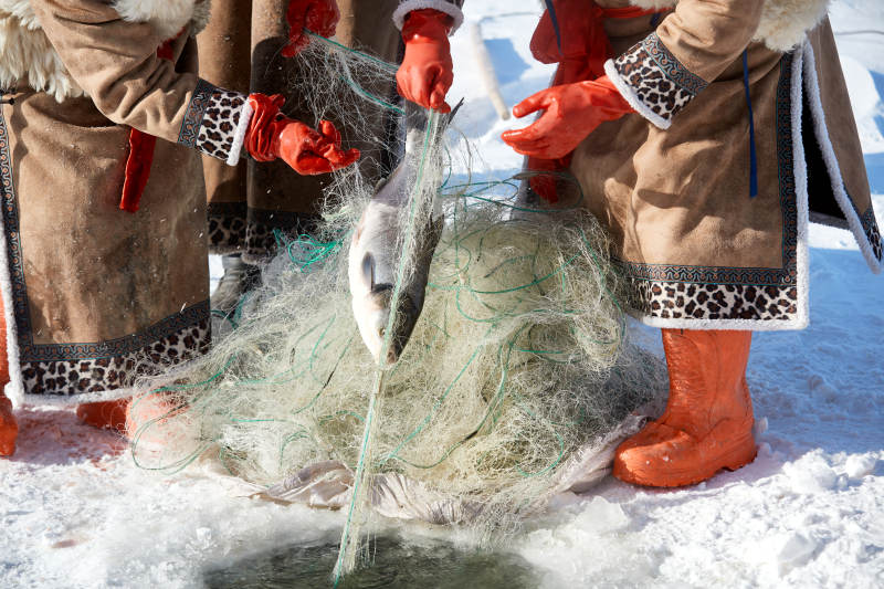 寒冷的冬季在冰冻的湖面上凿冰捕鱼