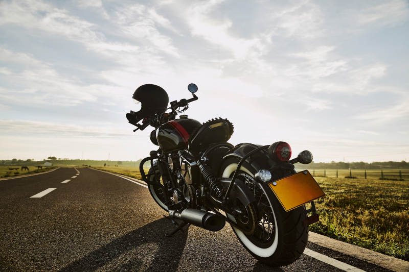 清晨朝阳下停靠在公路上的复古摩托车