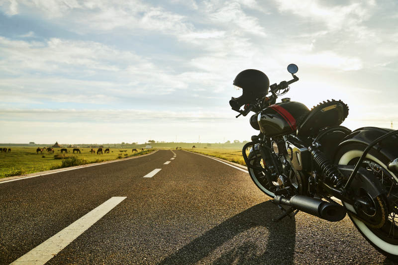 清晨朝阳下停靠在公路上的复古摩托车