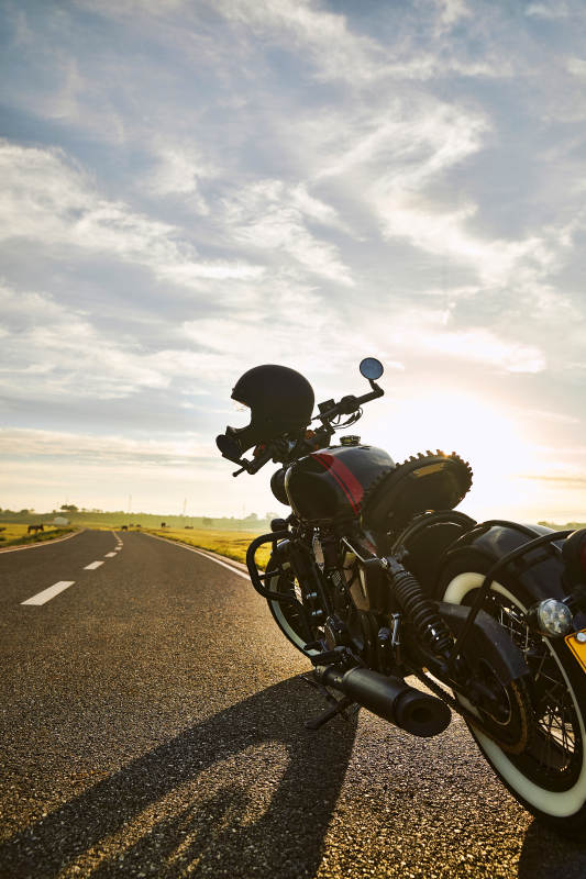 清晨朝阳下停靠在公路上的复古摩托车