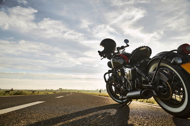 清晨朝阳下停靠在公路上的复古摩托车