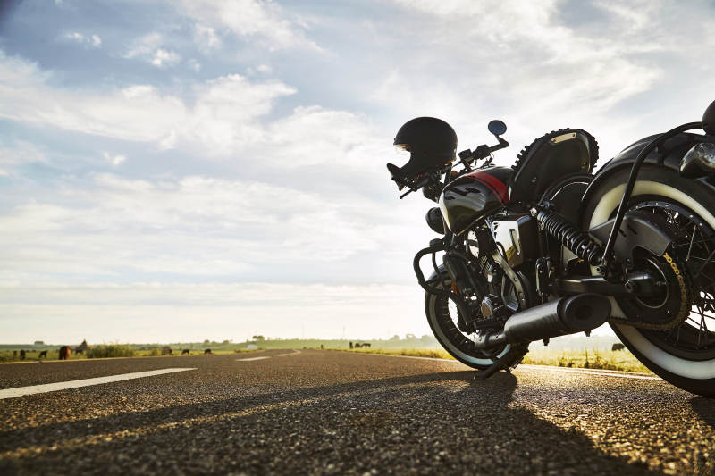 清晨朝阳下停靠在公路上的复古摩托车