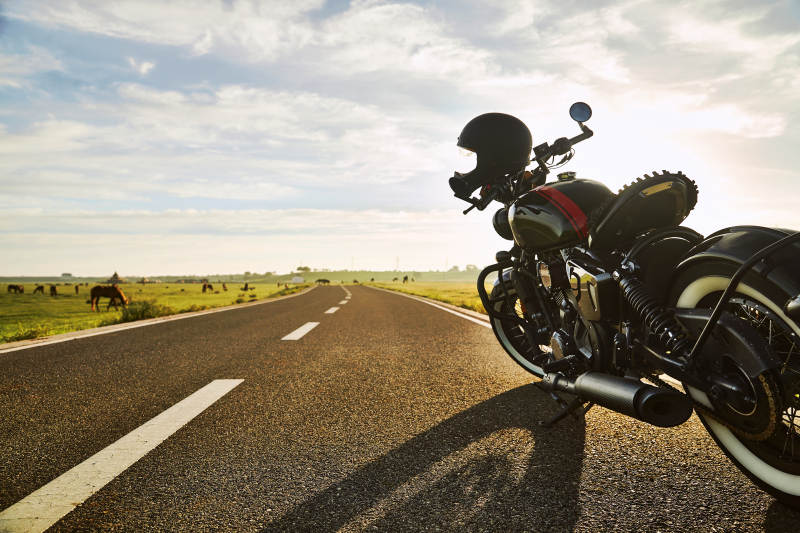 清晨朝阳下停靠在公路上的复古摩托车