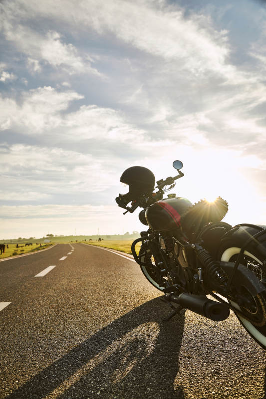 清晨朝阳下停靠在公路上的复古摩托车