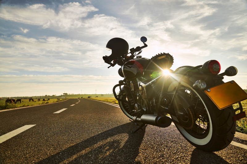 清晨朝阳下停靠在公路上的复古摩托车