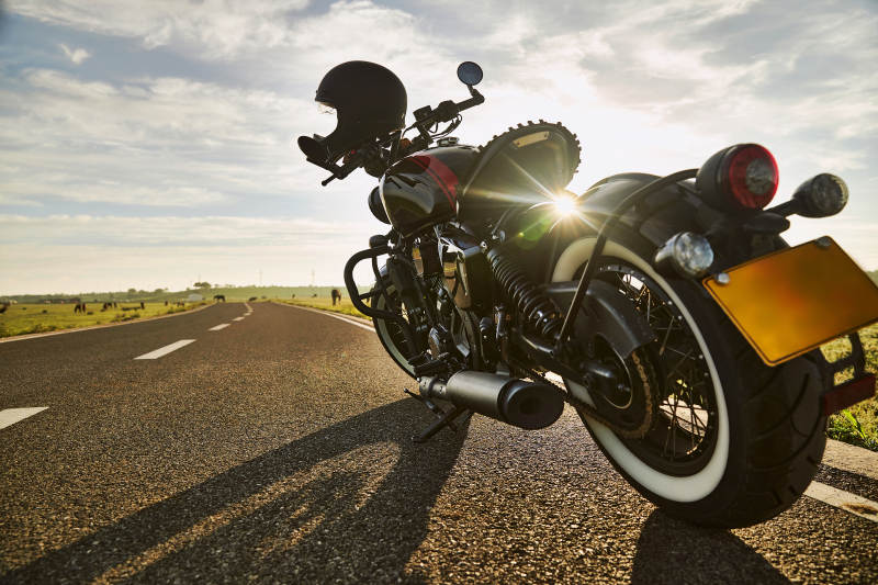 清晨朝阳下停靠在公路上的复古摩托车