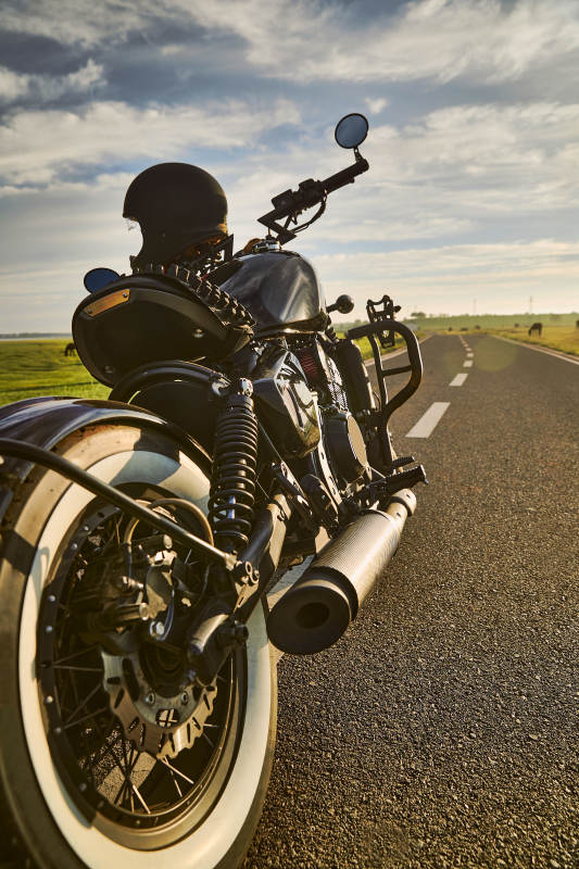 清晨朝阳下停靠在公路上的复古摩托车