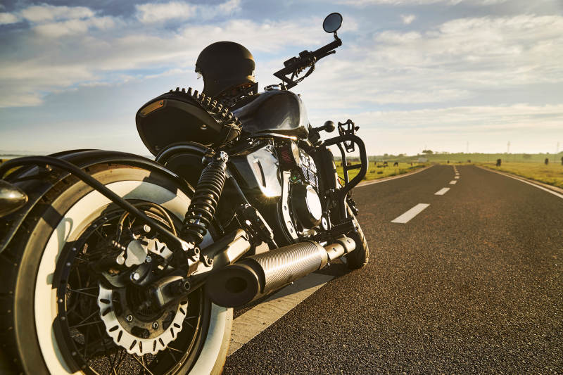 清晨朝阳下停靠在公路上的复古摩托车