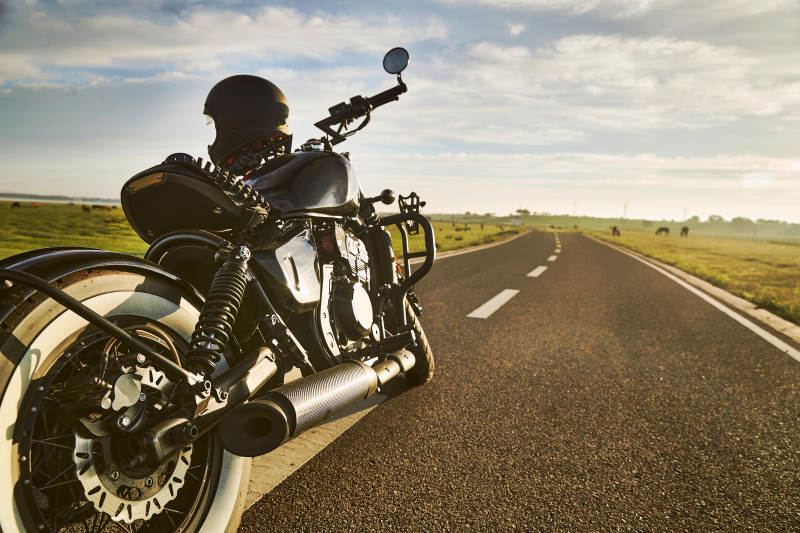 清晨朝阳下停靠在公路上的复古摩托车