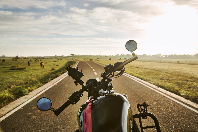 清晨朝阳下停靠在公路上的复古摩托车