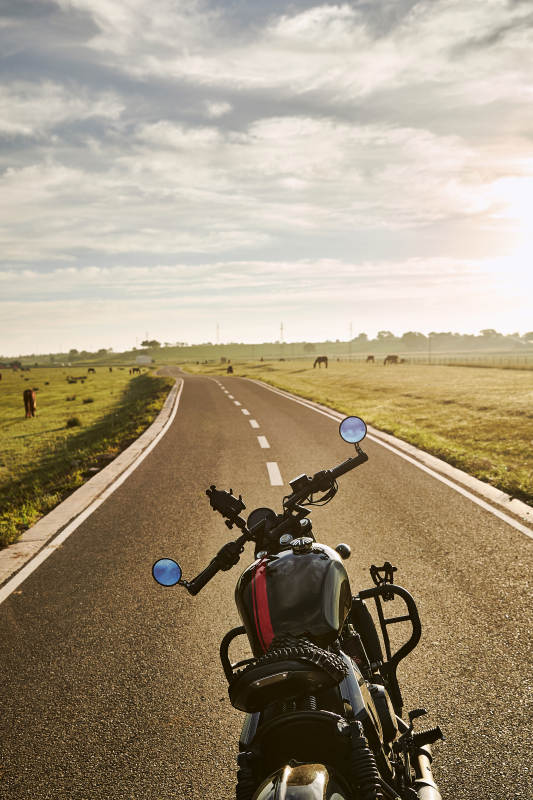 清晨朝阳下停靠在公路上的复古摩托车