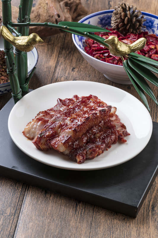 米花色瓷盘装的蜜汁叉烧肉摆放在樟木砧板上