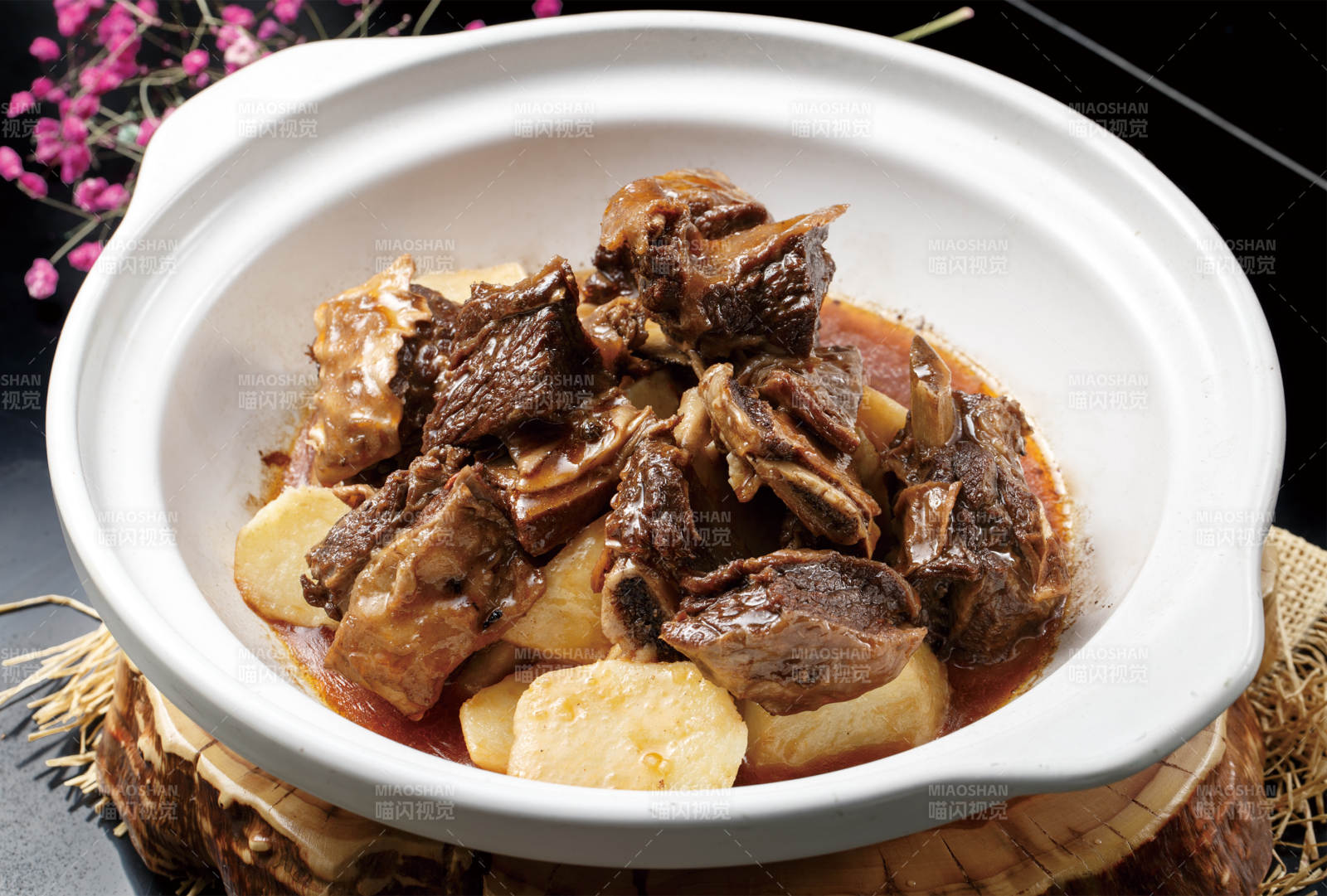 白色砂锅装的土豆烧牛排图片