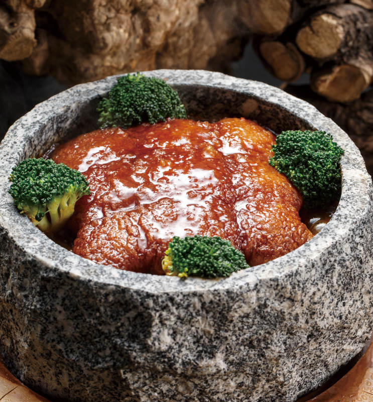 树墩上的摆放的石锅一品肉