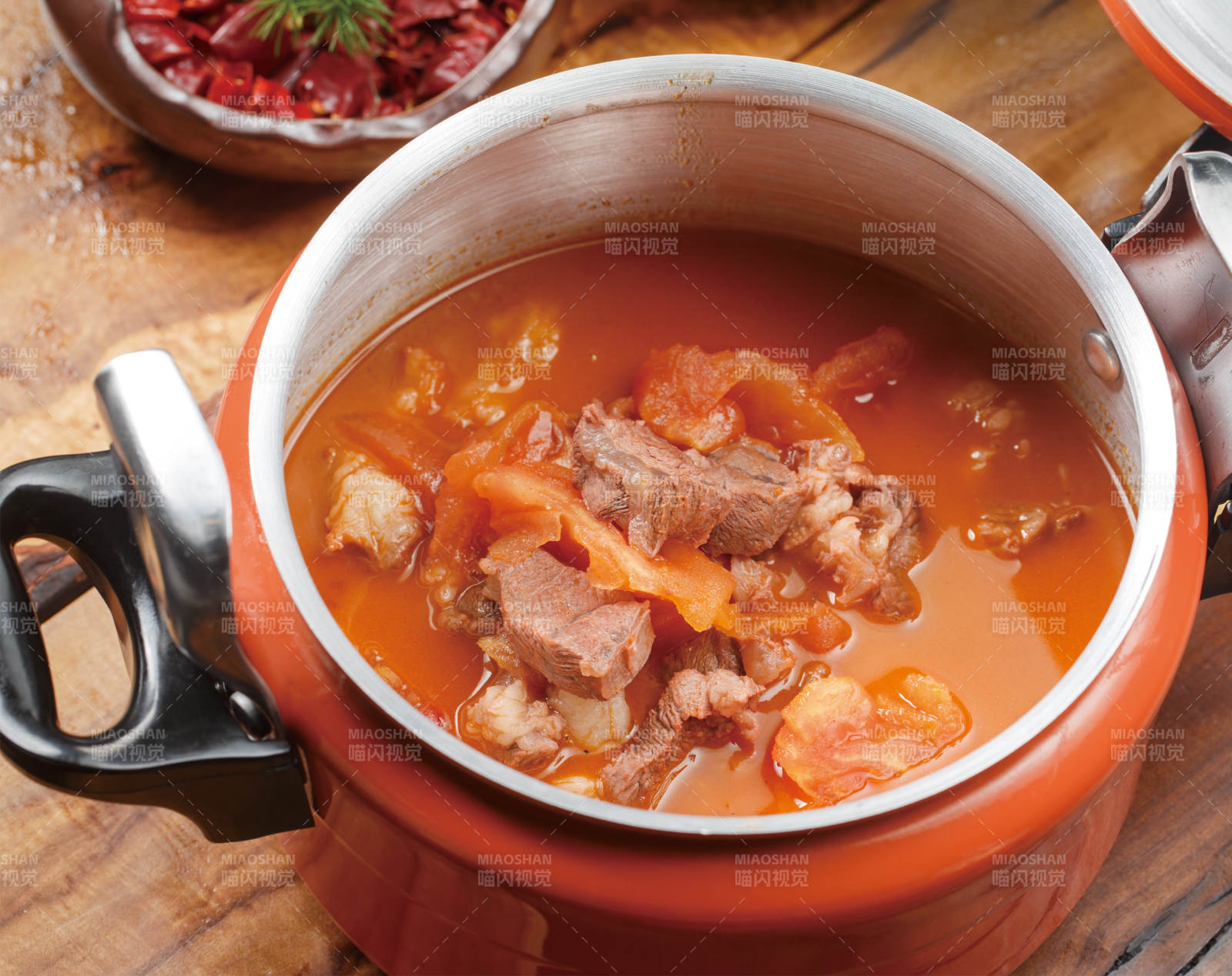 橙色不锈钢铁锅装的西红柿炖牛腩图片