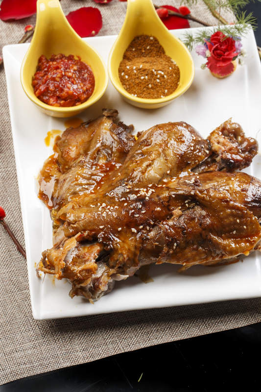 白色瓷盘装的特色蒙餐炭烤羊脊骨