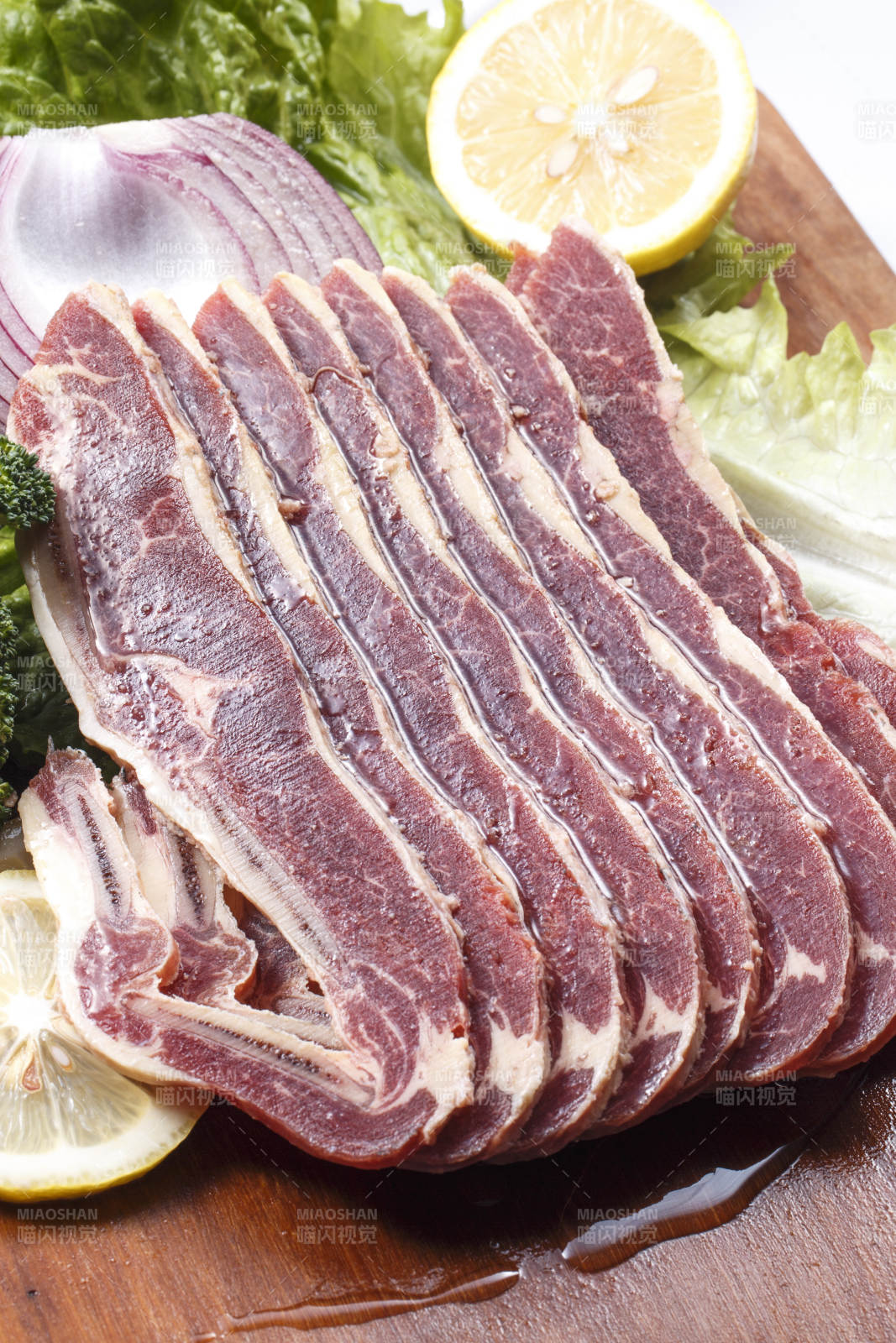 搭配柠檬洋葱生菜的牛肋排摆放在木质砧板上