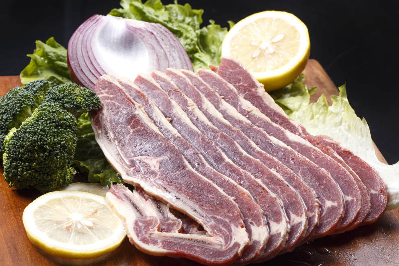 搭配柠檬洋葱生菜的牛肋排摆放在木质砧板上