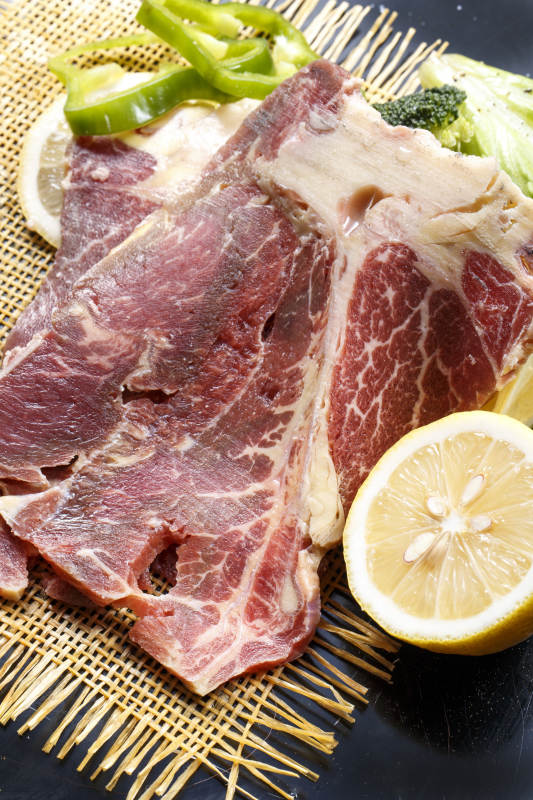 黑色背景草垫上的T骨牛排配柠檬