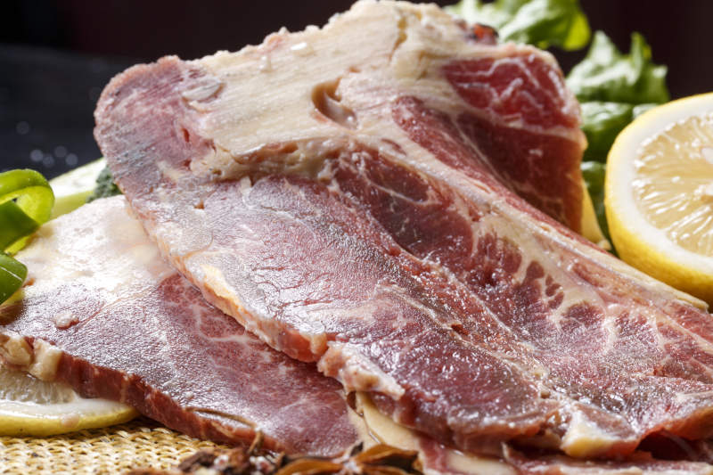 黑色背景草垫上的T骨牛排配柠檬