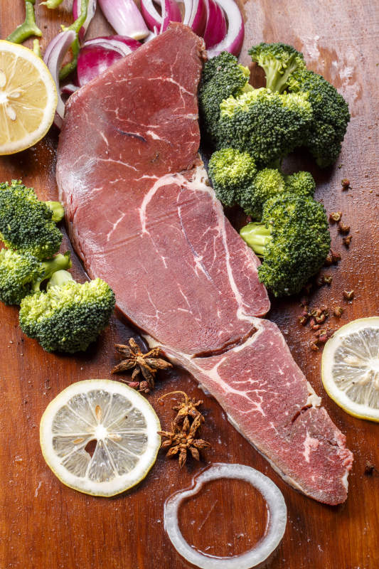 搭配柠檬西蓝花的牛膝圆肉摆放在木质砧板上