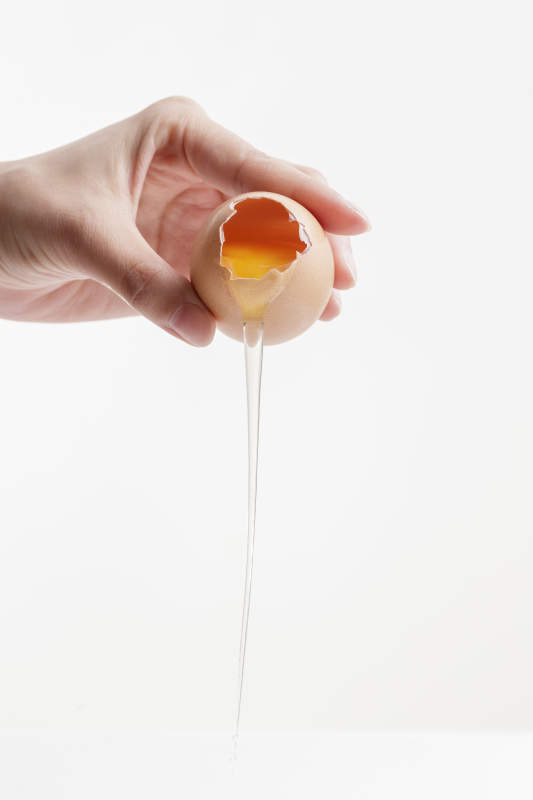手中的开口油鸡蛋将蛋清倒出