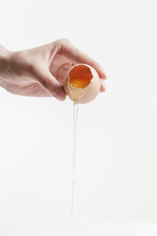 手中的开口油鸡蛋将蛋清倒出