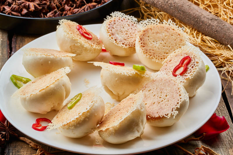 陈旧木板上的圆瓷盘装的水煎渔网酱肉包