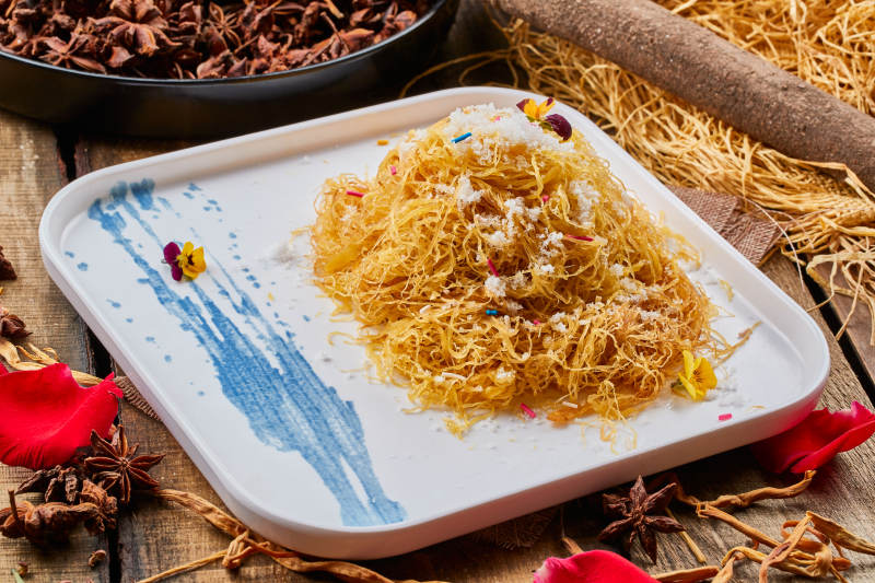 陈旧木板上的方瓷盘装的撒糖一窝丝-摄影图