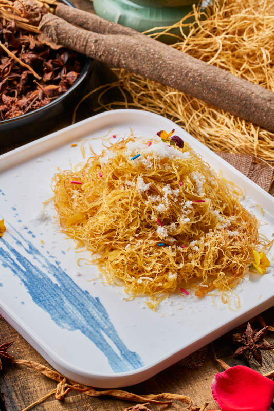 陈旧木板上的方瓷盘装的撒糖一窝丝-摄影图