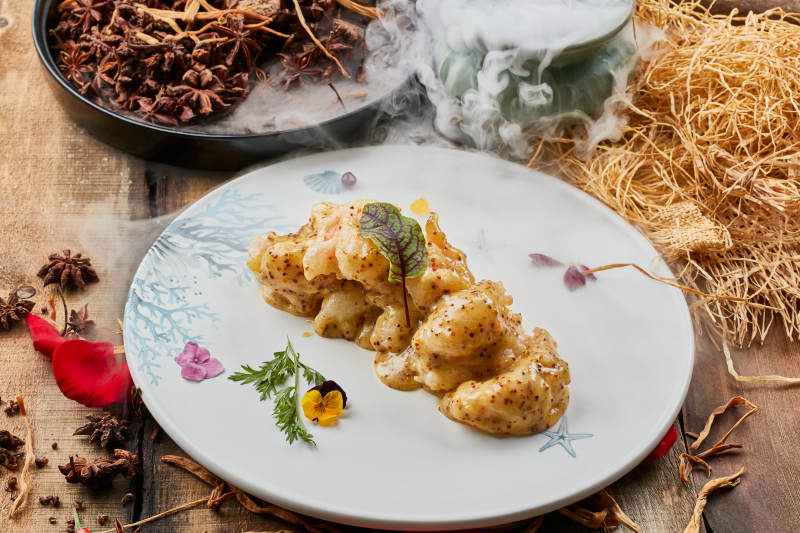 陈旧木板上的圆形瓷盘装的藜麦焗虾球