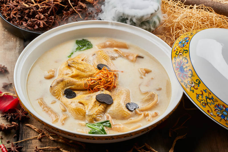 陈旧木板上的圆瓷汤盆装的花胶葛根炖柴鸡汤