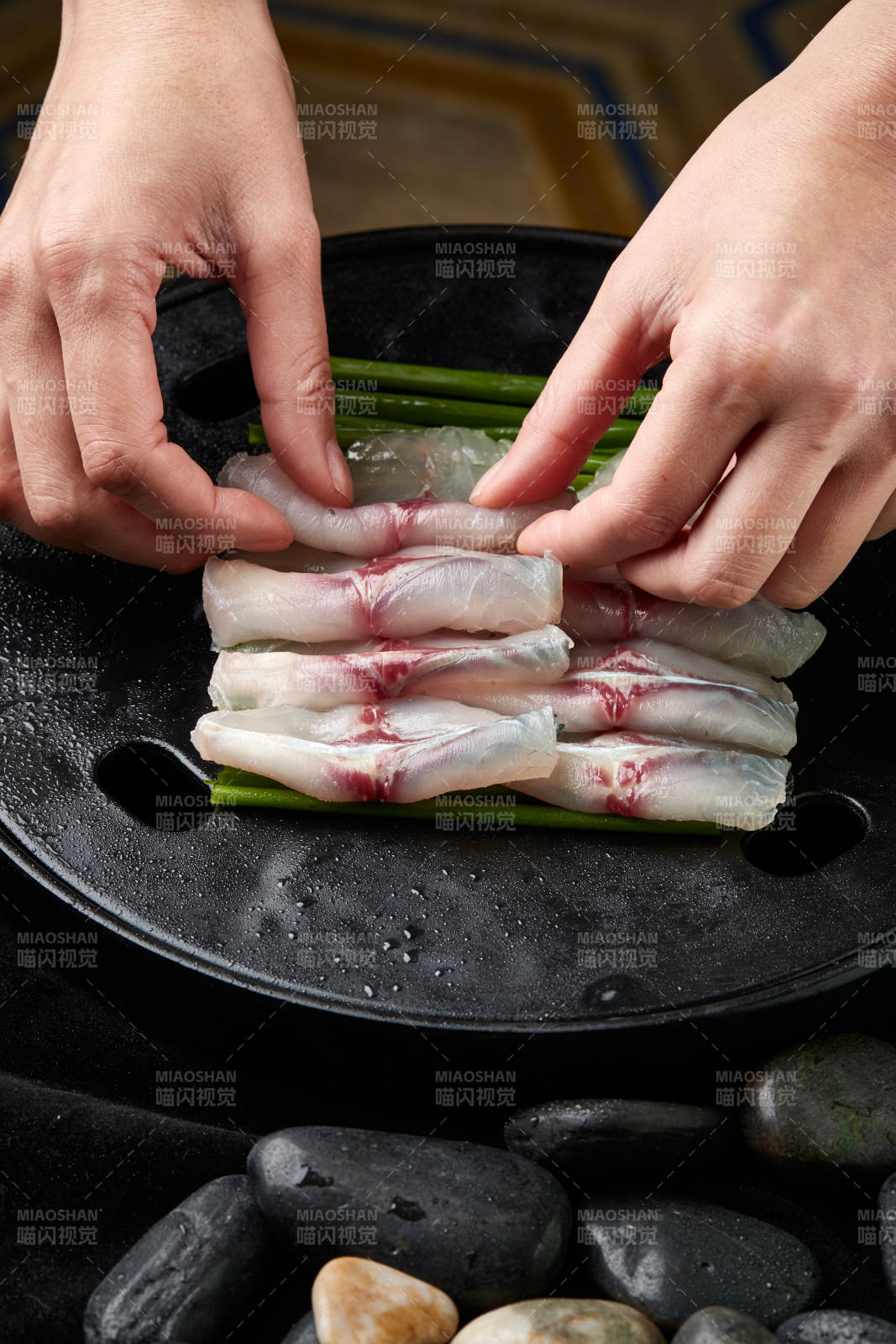 将晶莹白润的鲜鱼片码放在黑色的圆瓷盘上图片