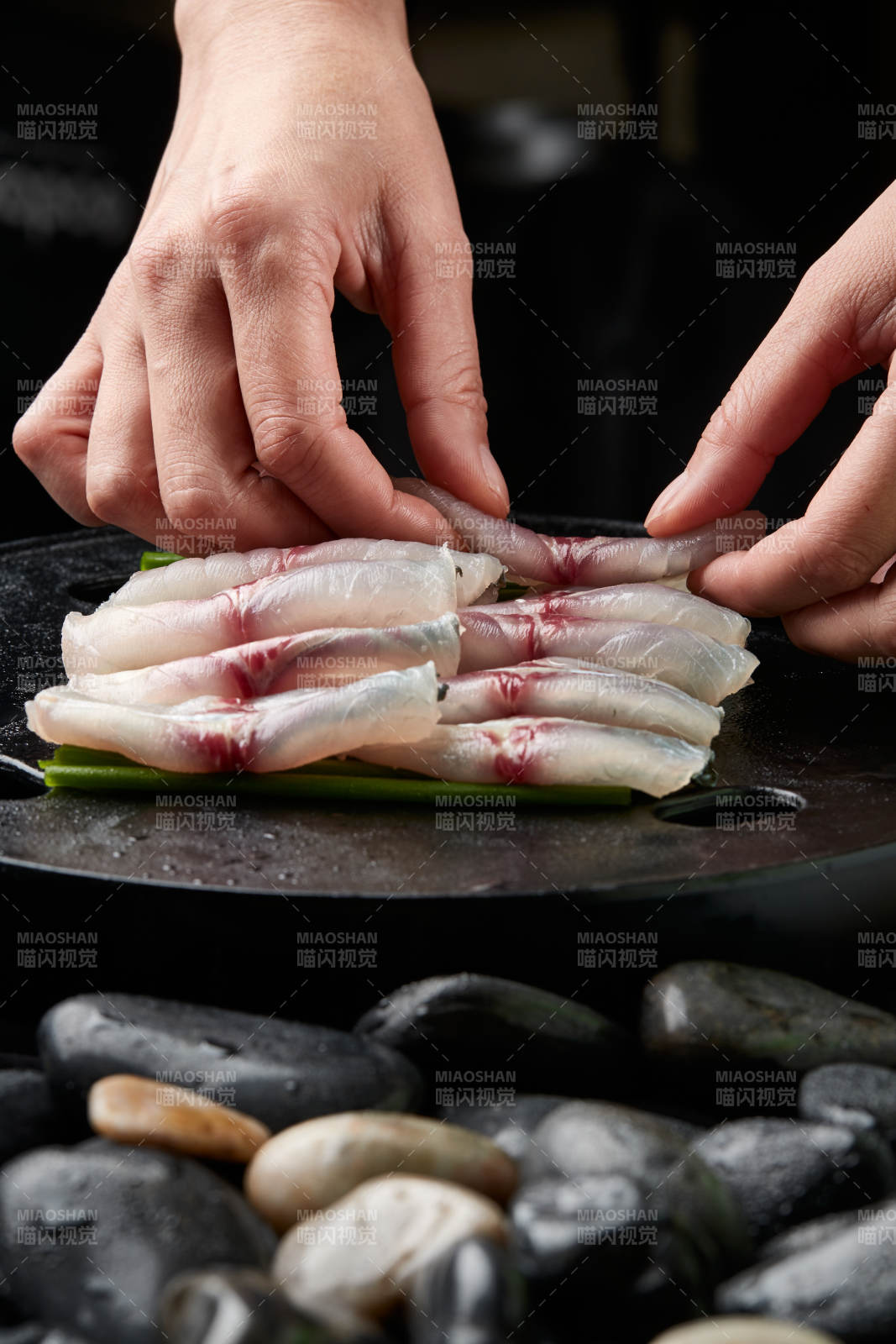 将晶莹白润的鲜鱼片码放在黑色的圆瓷盘上图片