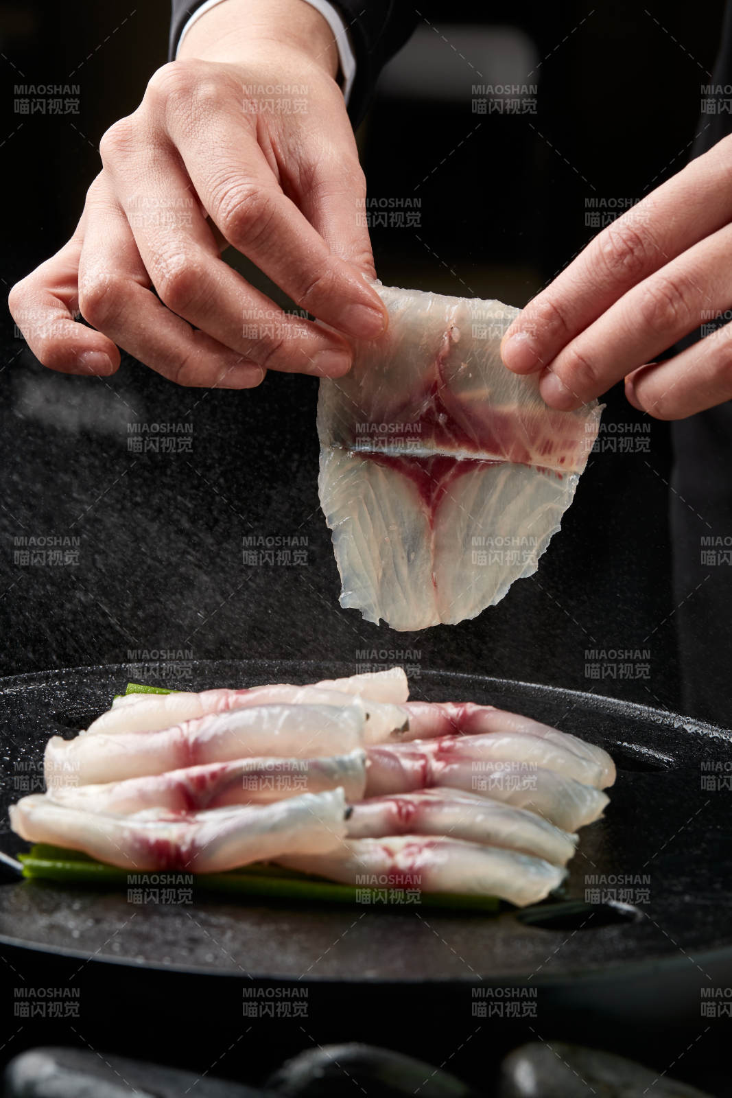 将晶莹白润的鲜鱼片码放在黑色的圆瓷盘上图片