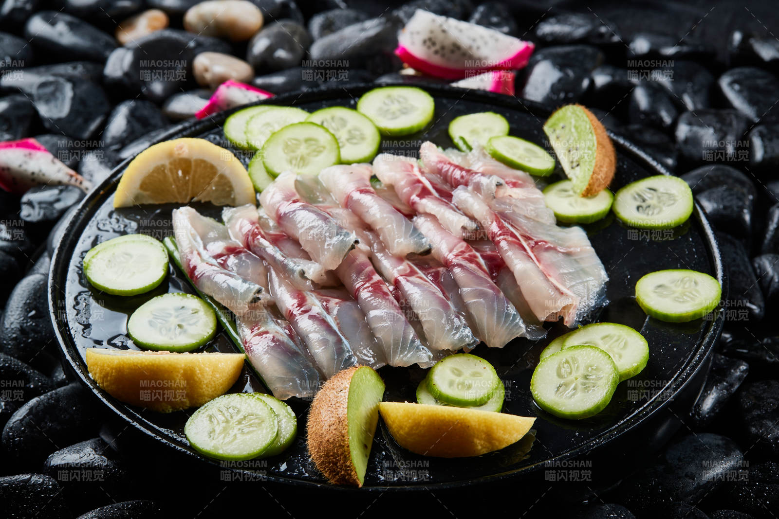 将晶莹白润的鲜鱼片码放在黑色的圆瓷盘上图片