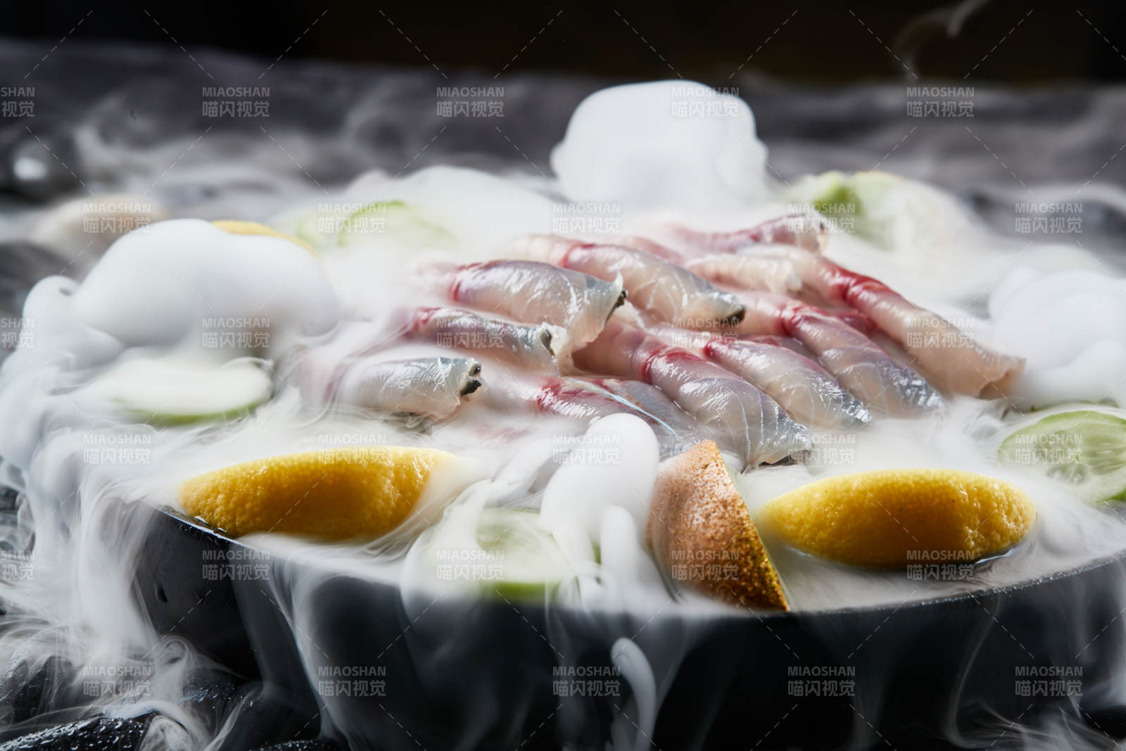 将晶莹白润的鲜鱼片码放在黑色的圆瓷盘上图片