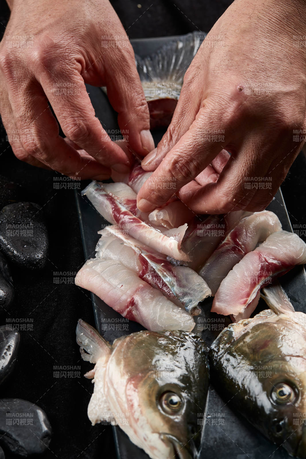 将晶莹白润的鲜鱼片码放在黑色的圆瓷盘上