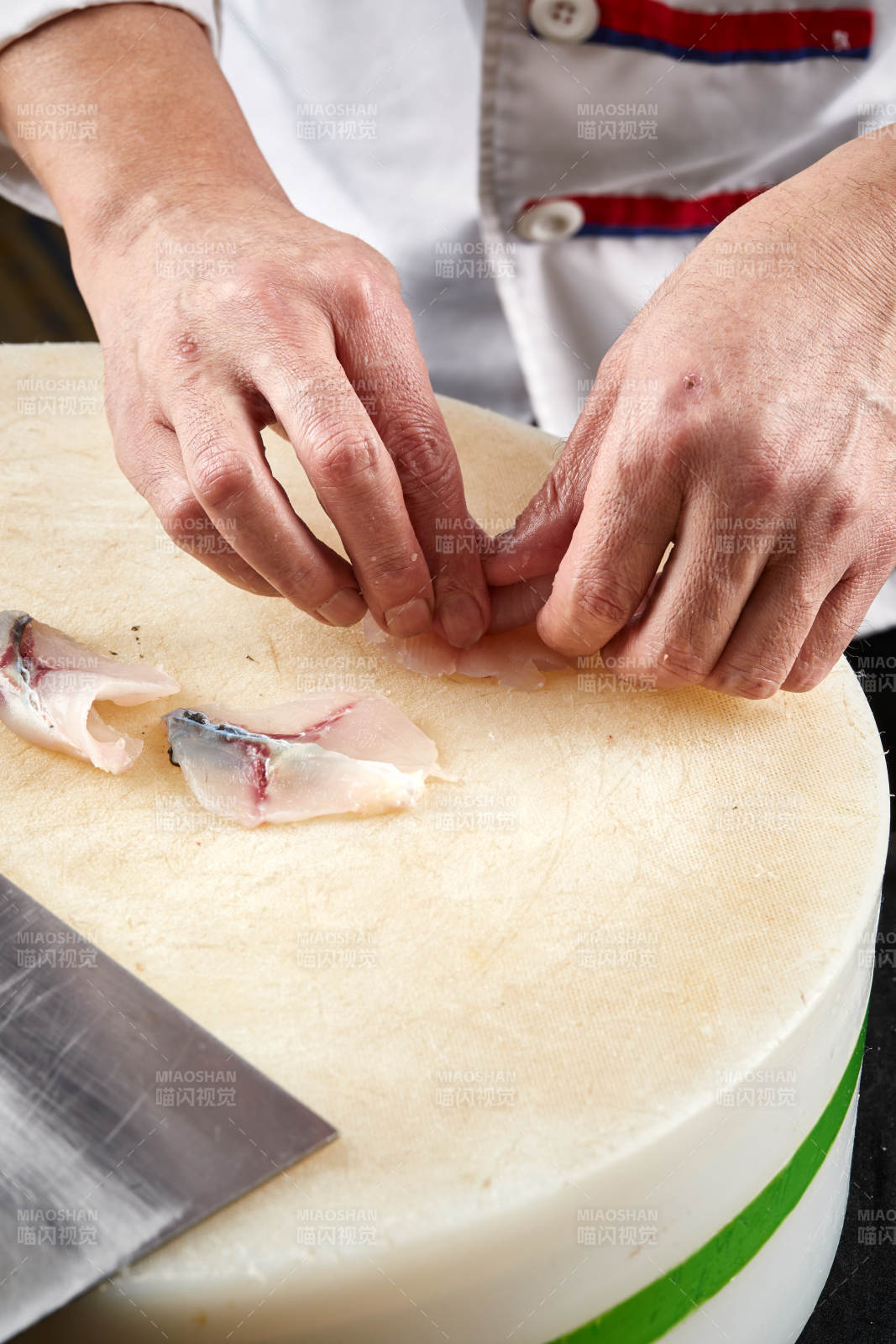 将晶莹白润的鲜鱼片码放在黑色的圆瓷盘上