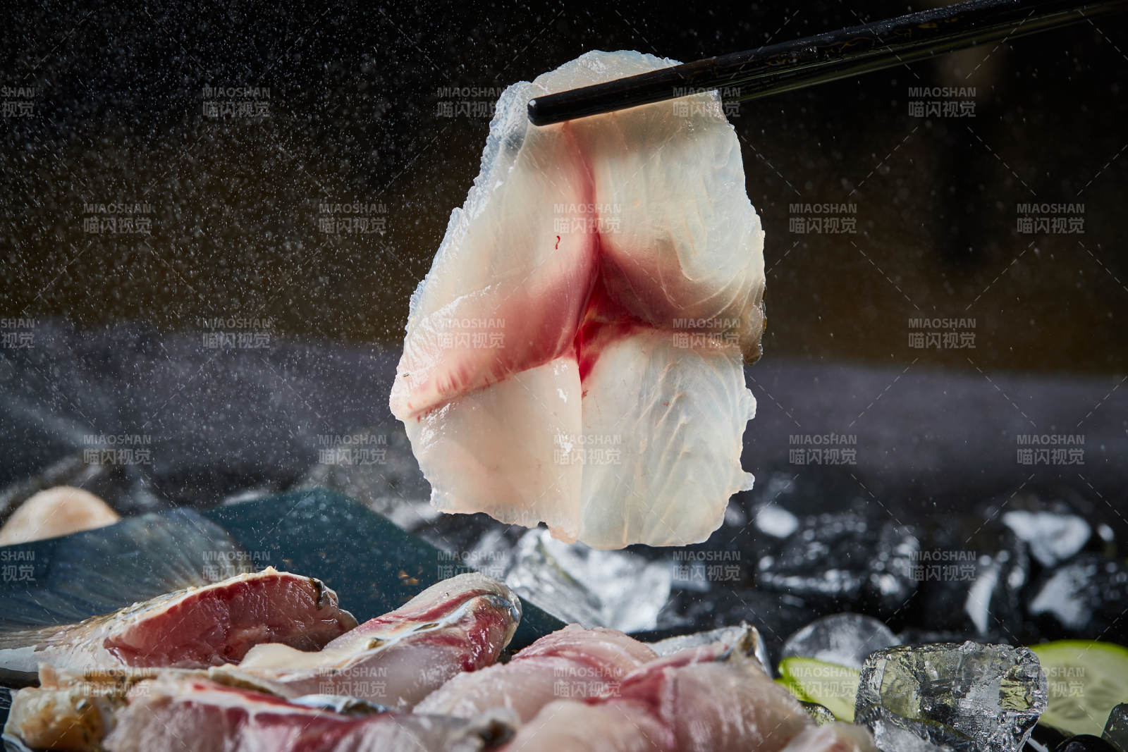 将晶莹白润的鲜鱼片码放在黑色的圆瓷盘上