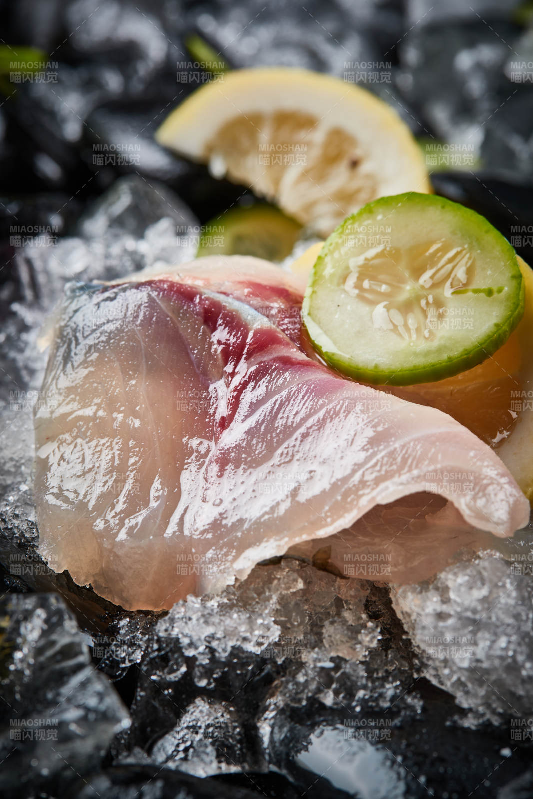 将晶莹白润的鲜鱼片码放在黑色的圆瓷盘上