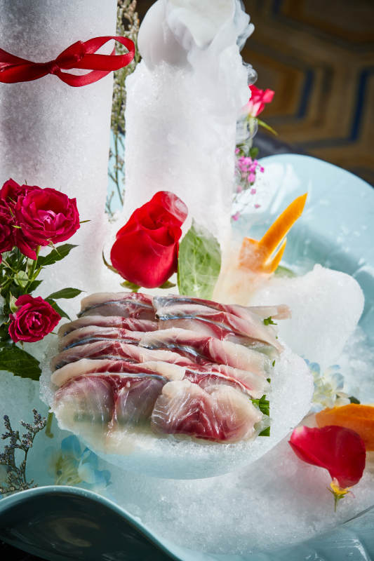 将晶莹白润的鲜鱼片码放在黑色的圆瓷盘上