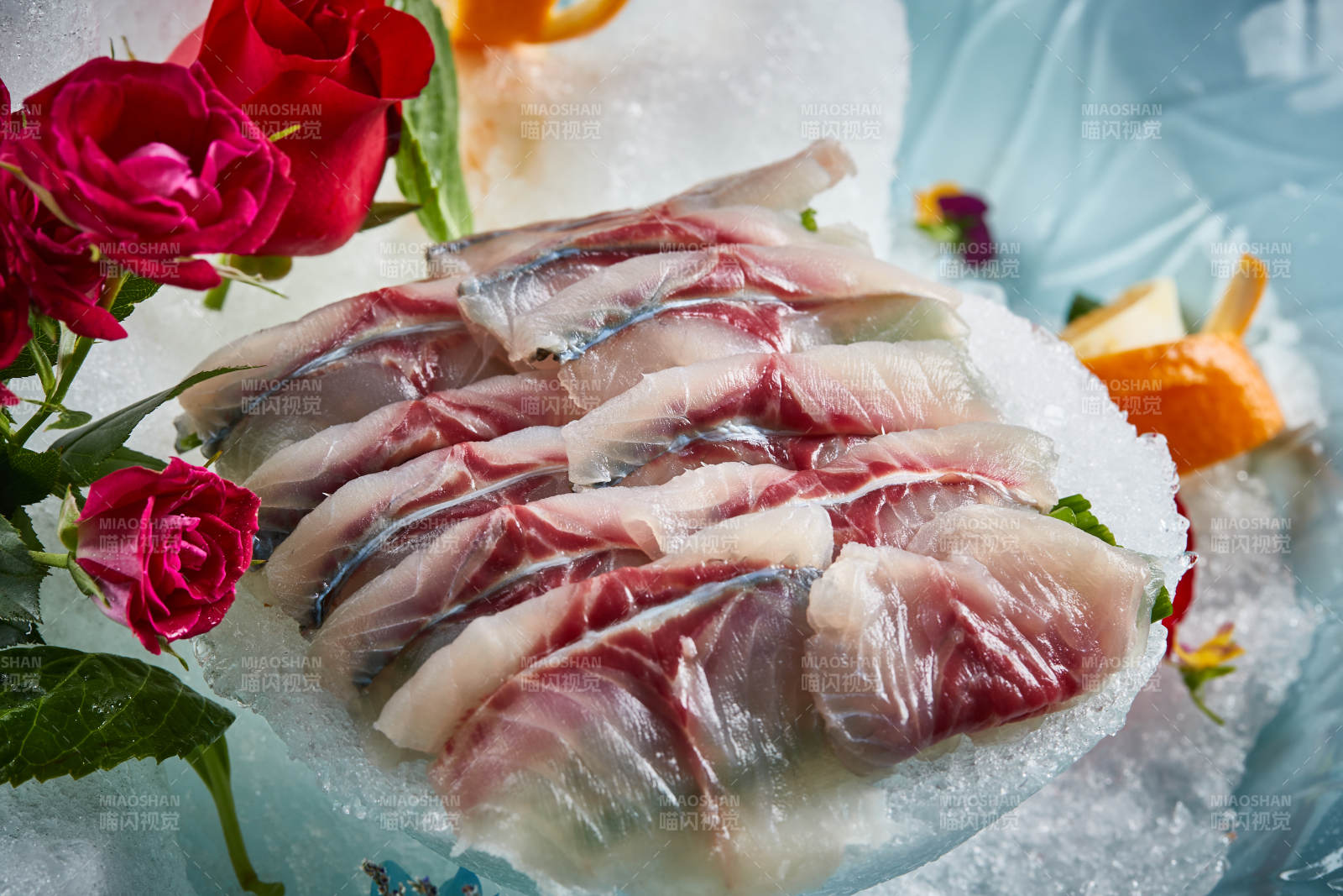 将晶莹白润的鲜鱼片码放在黑色的圆瓷盘上