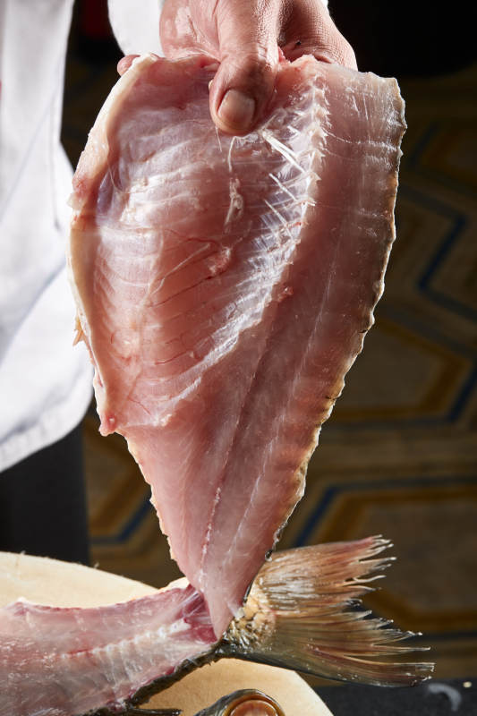 白色砧板上厨师用精湛的刀工展示生鱼片及鲜鱼料理切割分切的刀工