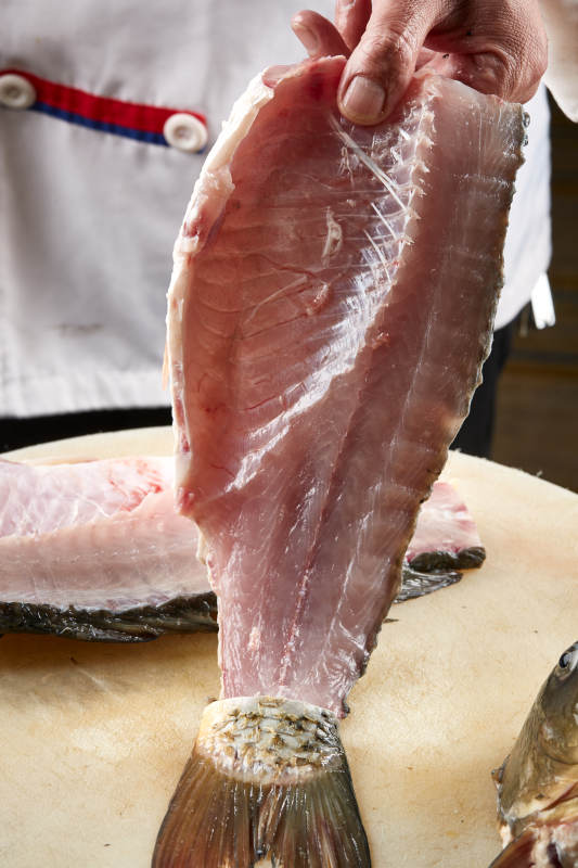 白色砧板上厨师用精湛的刀工展示生鱼片及鲜鱼料理切割分切的刀工