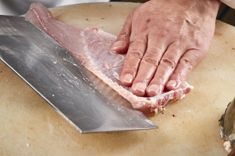 白色砧板上厨师用精湛的刀工展示生鱼片及鲜鱼料理切割分切的刀工