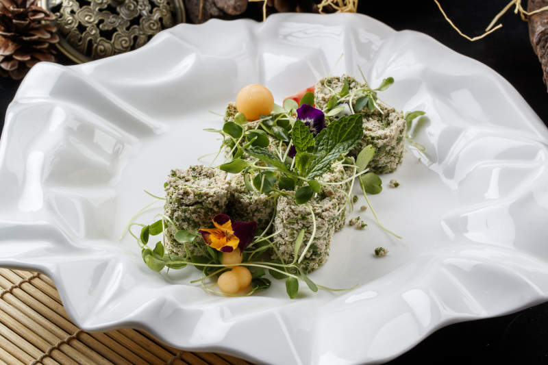 壽司簾上的花邊瓷盤裝的香椿苗麻豆腐